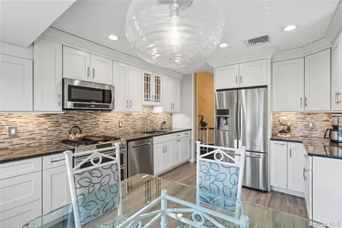 a kitchen with granite countertop a refrigerator a sink a stove a microwave and island