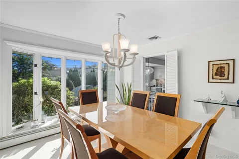 a view of a dining room with furniture large windows wooden floor and chandelier