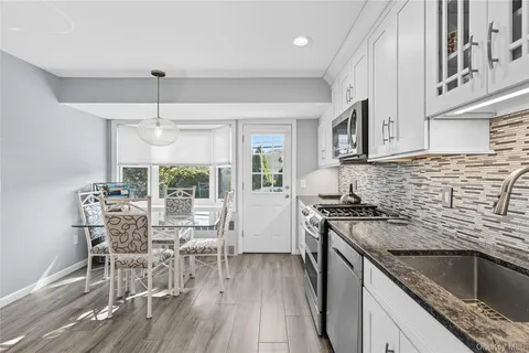 a kitchen with stainless steel appliances granite countertop a stove top oven a sink dishwasher a dining table and chairs with wooden floor