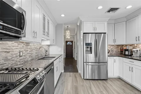 a kitchen with granite countertop stainless steel appliances a refrigerator a stove top oven and wooden floors