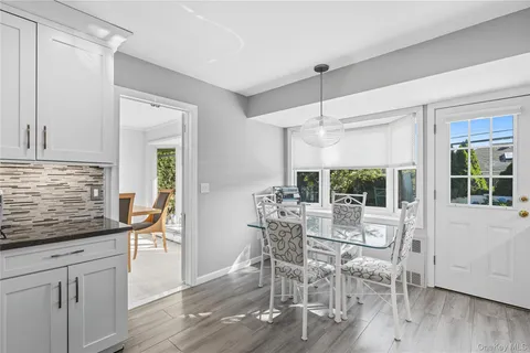 a view of a white kitchen with wooden floor and stainless steel appliances