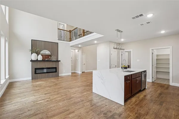 a large white kitchen with wooden floor and stainless steel appliances