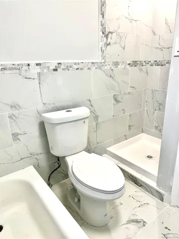 a white toilet sitting next to a bath tub and shower