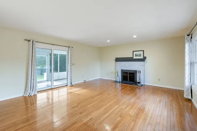 a view of a room with wooden floor a fireplace and windows