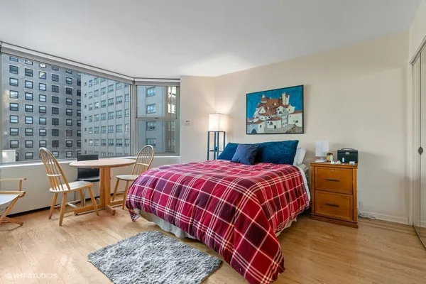 a bedroom with a bed a table and a large window