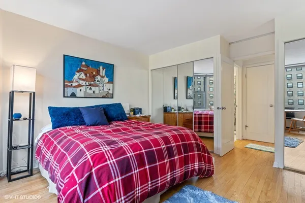 a bedroom with a bed a dresser and wooden floor