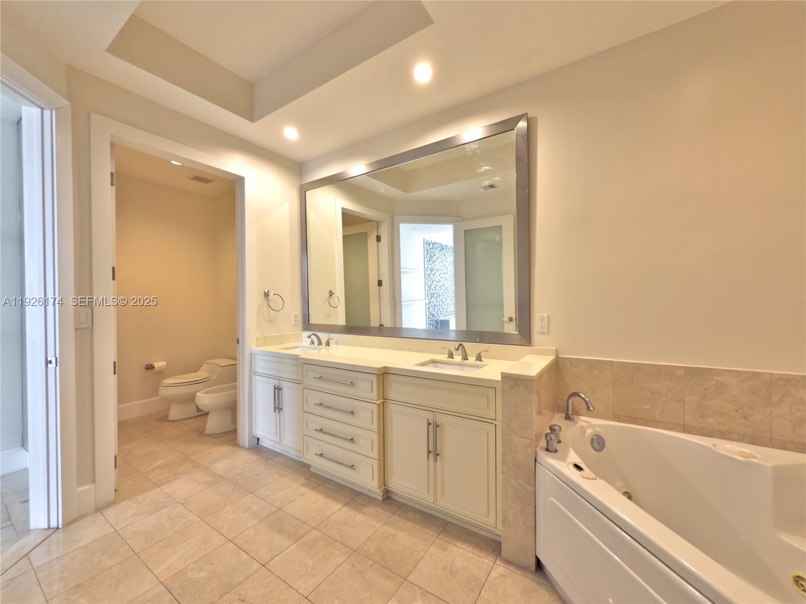 848 Brickell Key Drive, Unit 306 Miami, FL 33131 - Photo 19 of 66 a bathroom with a tub sink toilet and a mirror