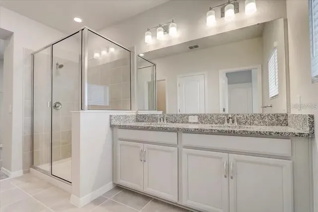 a bathroom with a granite countertop sink a mirror and shower