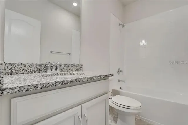 a bathroom with a granite countertop sink a toilet and a bathtub