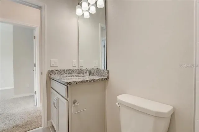 a bathroom with a granite countertop sink and a toilet