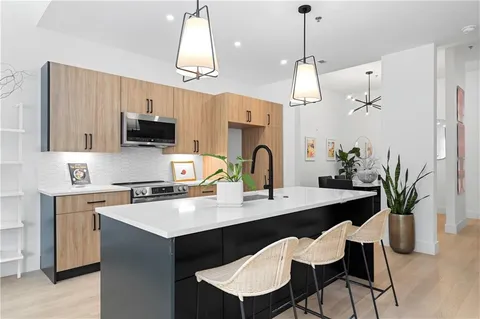 a kitchen with stainless steel appliances a table chairs refrigerator and microwave