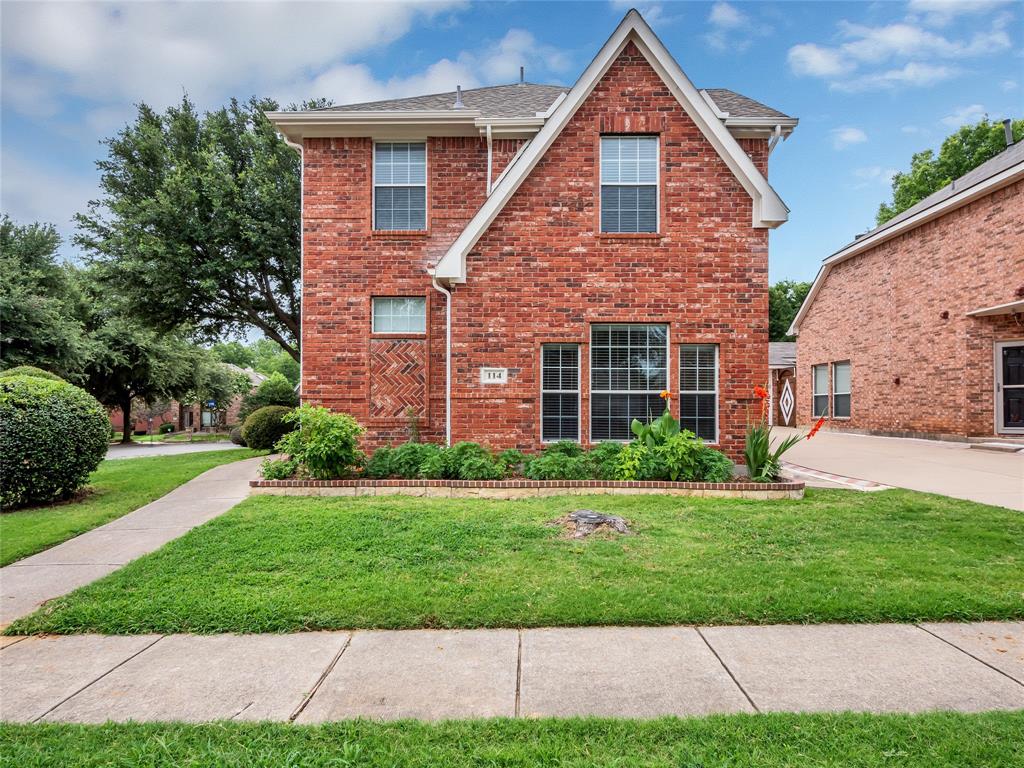 Traditional home with a front yard, brick siding, and a shingled roof