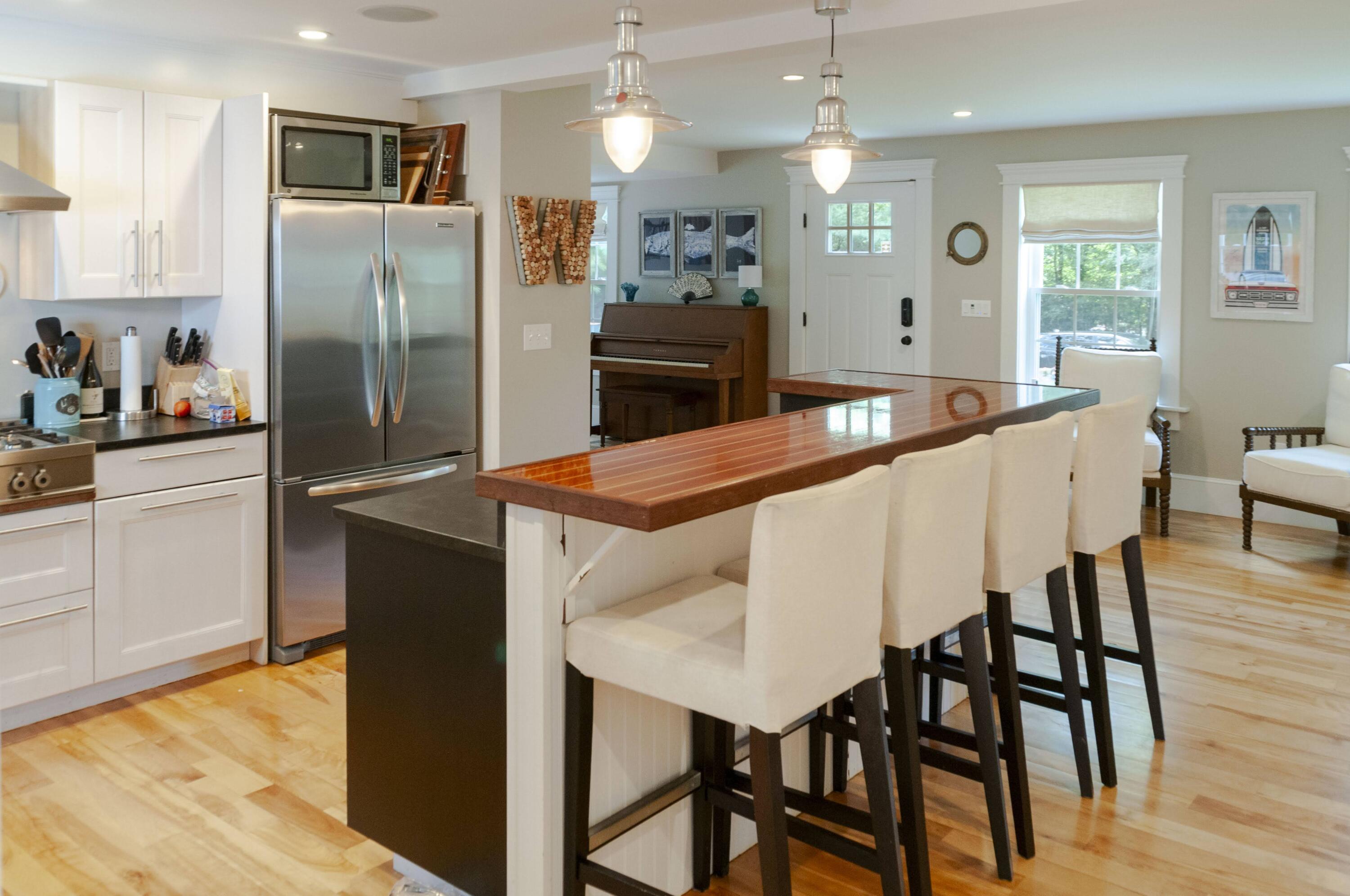 1774 South County Road Osterville, MA 02655 - Photo 24 of 75 a kitchen with stainless steel appliances kitchen island granite countertop a refrigerator a stove a microwave oven a dining table and chairs with wooden floor