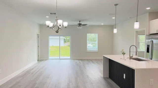 a kitchen with kitchen island a sink wooden floor and a chandelier