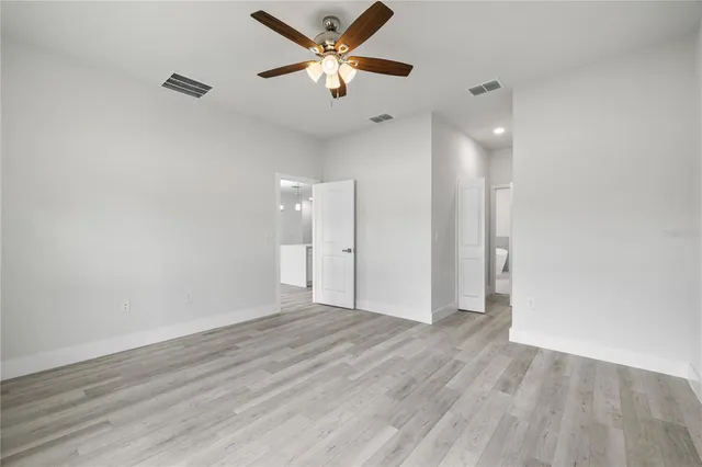 a view of an empty room and window a ceiling fan and wooden floor