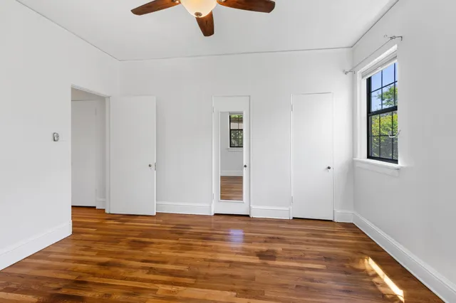 a view of an empty room with wooden floor and a window