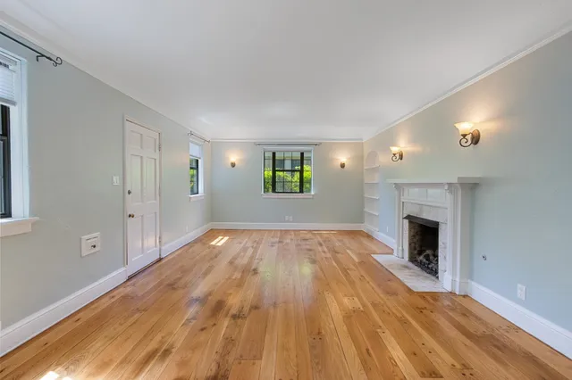 a view of empty room with wooden floor and fireplace