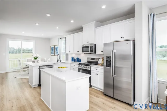 a kitchen with a refrigerator a sink dishwasher a stove and white cabinets with wooden floor