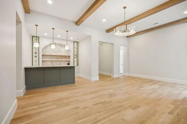 a view of an empty room with kitchen and a window
