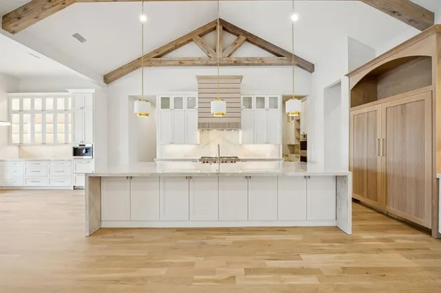 a view of a kitchen with kitchen island a sink wooden floor and a refrigerator