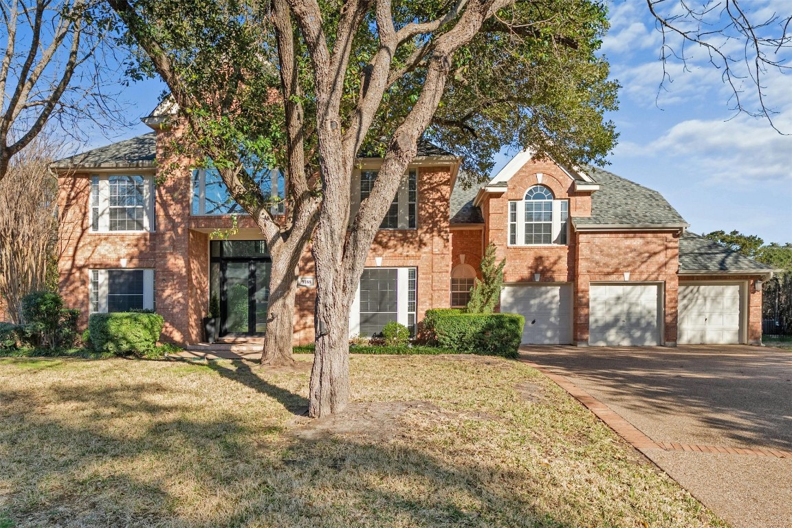 Impressive curb appeal with mature shade trees, brick exterior and attached THREE car garage