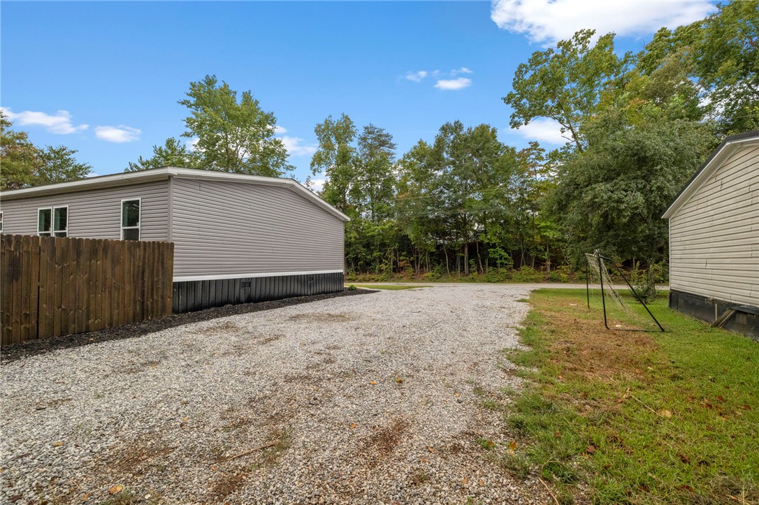 474 Bryant Road Pelzer, SC 29669 - Photo 37 of 44 Ample gravel parking spans between the homes against a backdrop of mature trees.