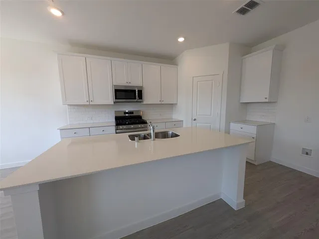 a kitchen with kitchen island a sink a stove and cabinets