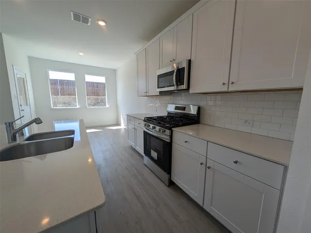 a view of a kitchen with a sink dishwasher cabinets and wooden floor