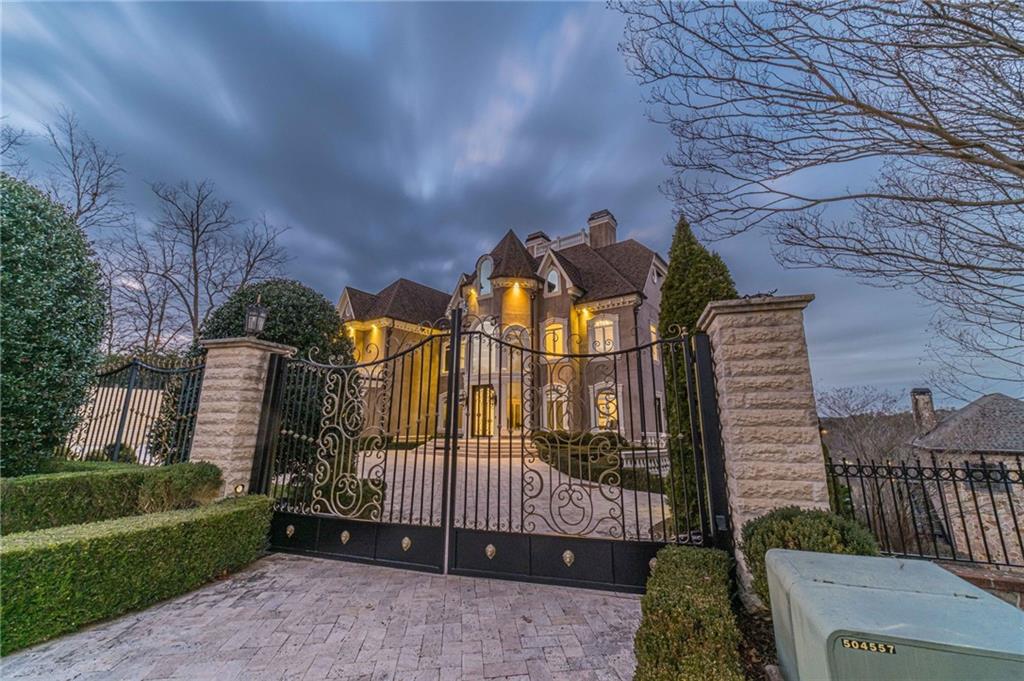 a view of a brick house with a small yard and a large tree