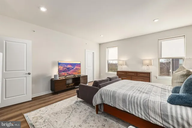 a bedroom with a bed couch and wooden floor