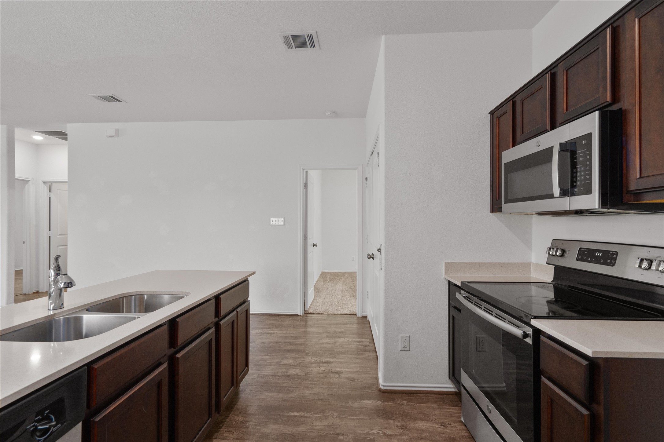 791 Circle Way Jarrell, TX 76537 - Photo 12 of 36 Kitchen featuring dark wood cabinetry, light-toned countertops, stainless steel appliances, and a double basin sink with a chrome faucet