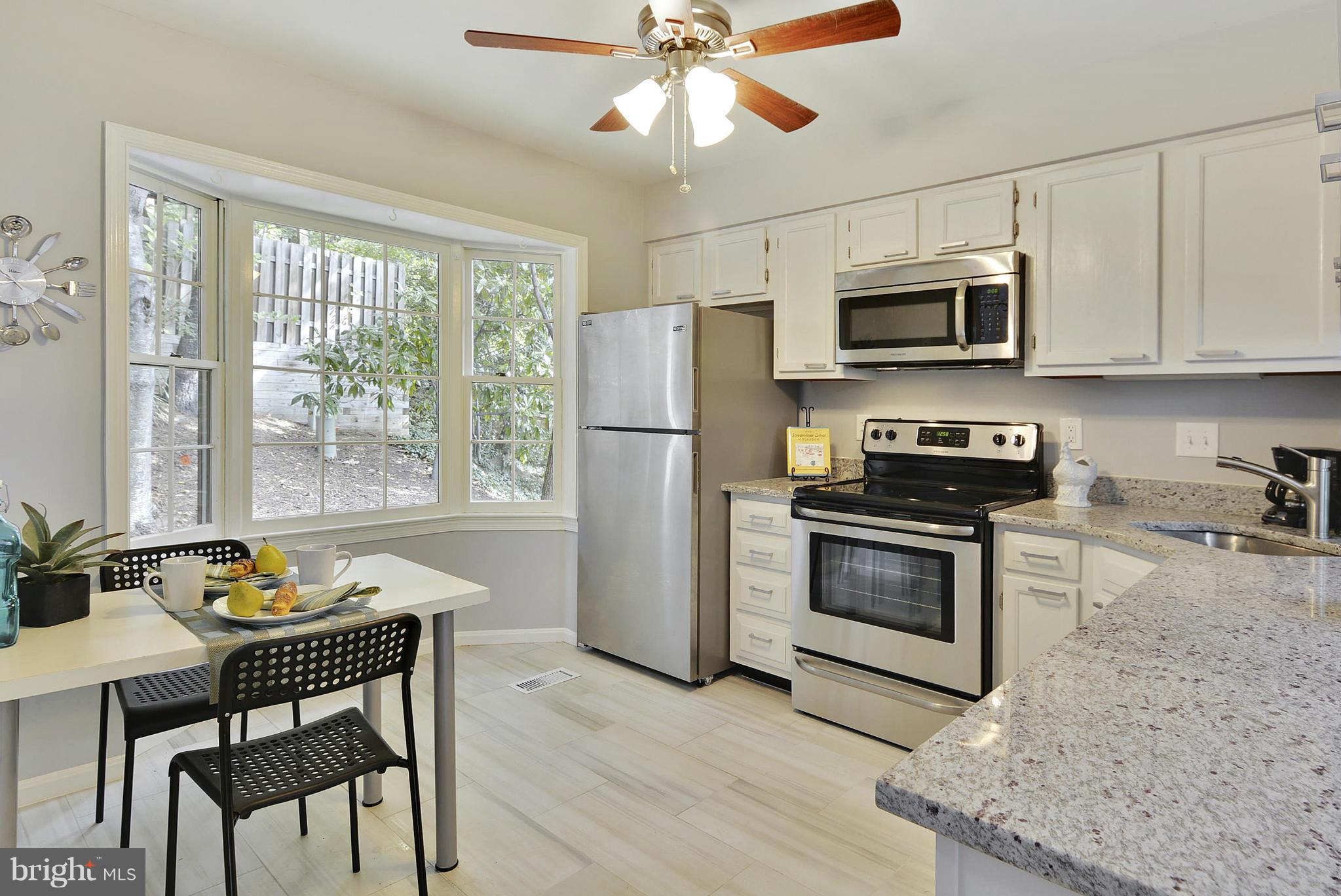 2059 South Glebe Road Arlington, VA 22206 - Photo 1 of 20 a kitchen with stainless steel appliances granite countertop a stove a refrigerator a microwave a dining table and chairs with wooden floor