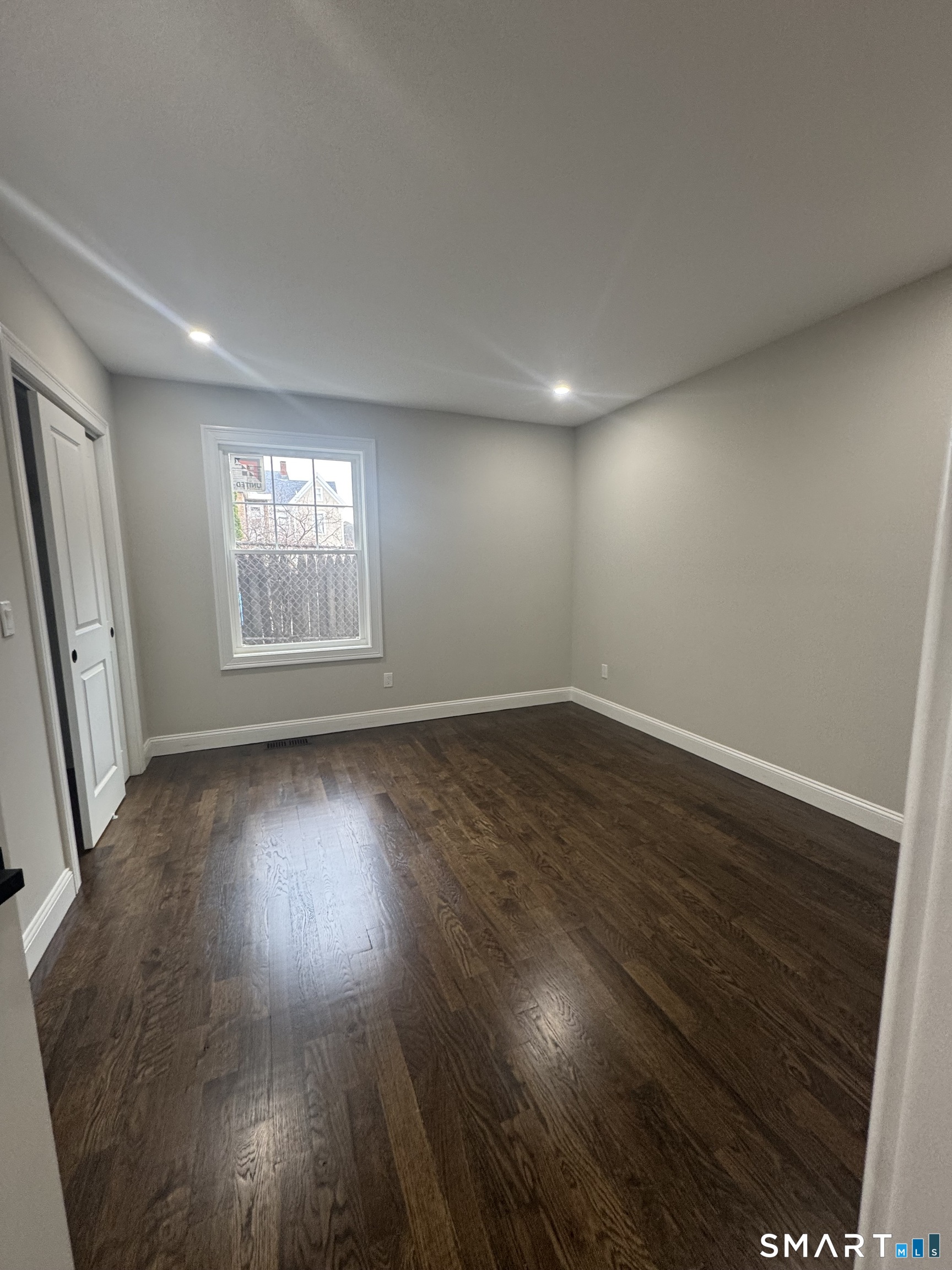 279 Harriet Street Bridgeport, CT 06608 - Photo 8 of 9 an empty room with wooden floor and windows