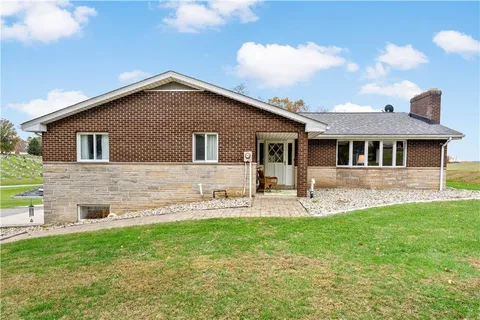 a front view of a house with a yard and chairs
