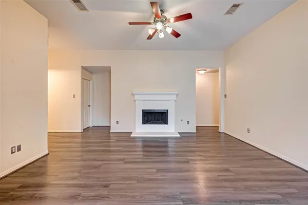 a view of an empty room with wooden floor and a fireplace