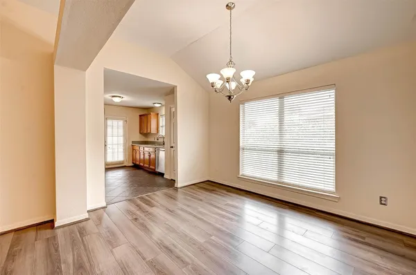 a view of a livingroom with wooden floor and a kitchen