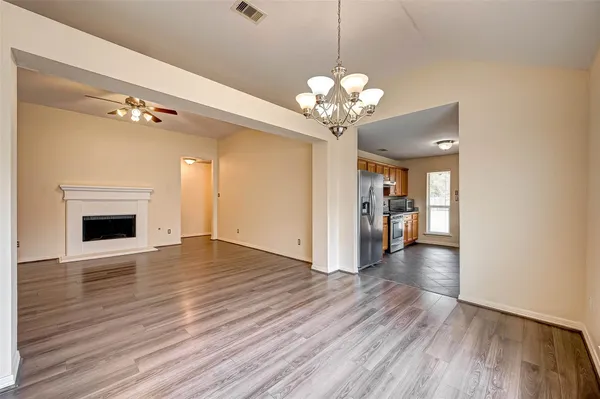 a view of an empty room with wooden floor and a kitchen