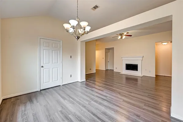 a view of an empty room with wooden floor and a kitchen