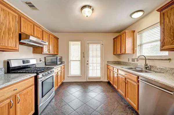 a large kitchen with stainless steel appliances granite countertop a stove a sink and a granite counter tops