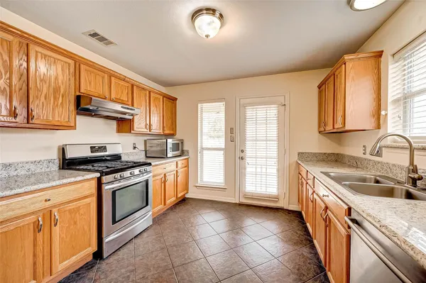 a kitchen with stainless steel appliances granite countertop a stove a sink and a refrigerator