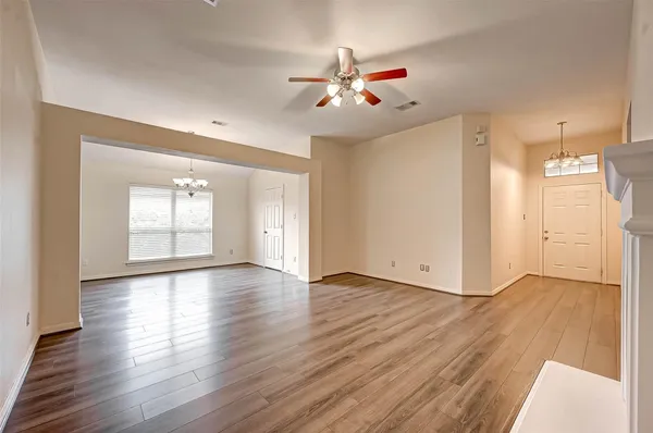 a view of an empty room with wooden floor and a window