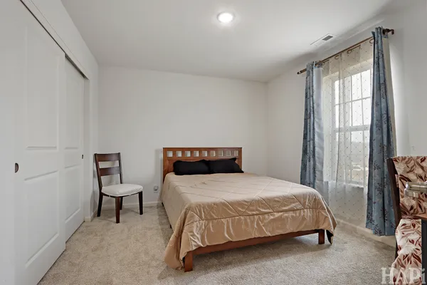 a bedroom with a bed a chair and next to a window