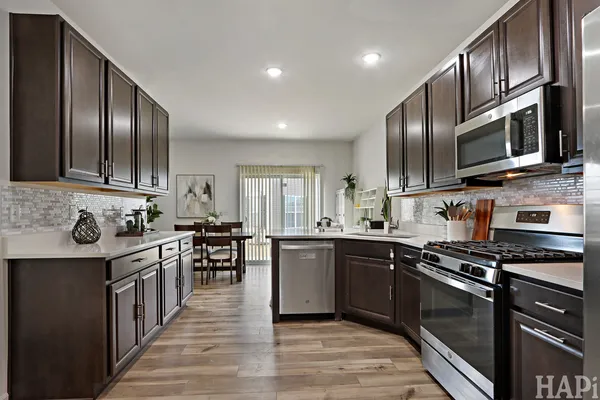 a kitchen with stainless steel appliances granite countertop a stove top oven a sink dishwasher a refrigerator and cabinets with wooden floor