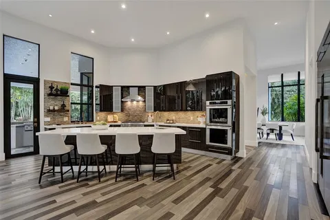 a living room with furniture a large window and wooden floor