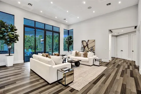 a living room with furniture large windows and wooden floor