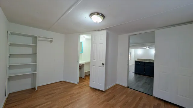 a view of an empty room with wooden floor & cabinets