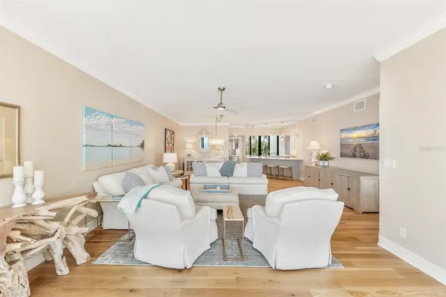 a large white kitchen with a large island oven a sink dishwasher white cabinets and couches