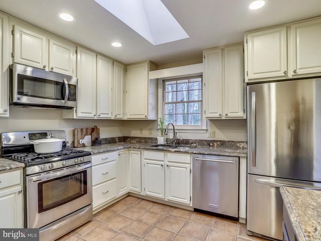 a kitchen with cabinets stainless steel appliances and a window