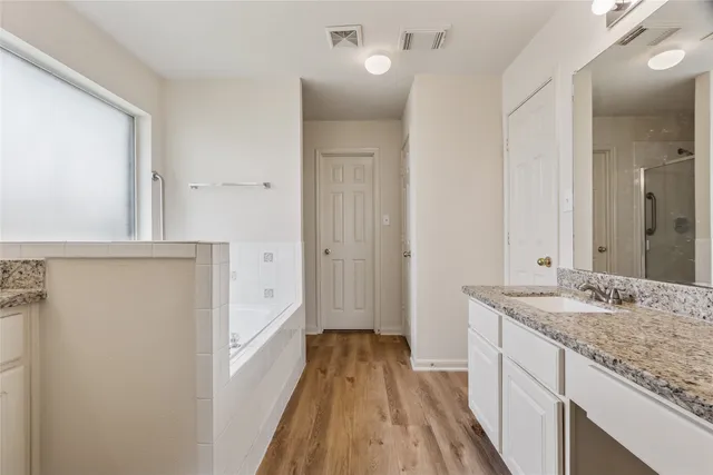 a bathroom with a granite countertop double vanity sink and a mirror
