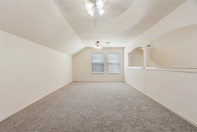 an empty room with chandelier fan and windows